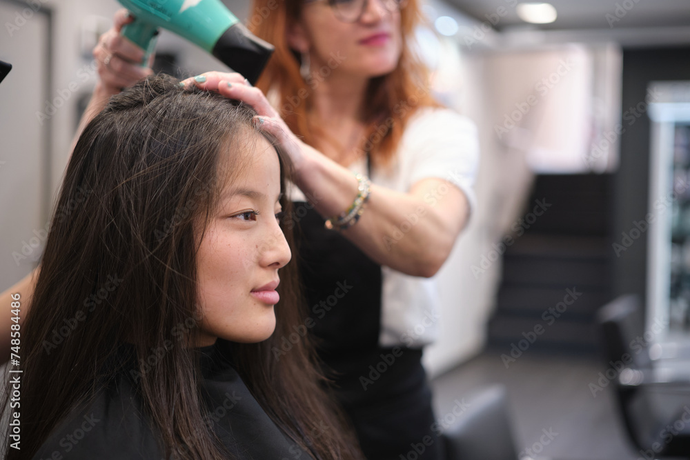 Chinese woman sitting while hairdresser drying her hair Chinese woman sitting while hairdresser drying her hair
