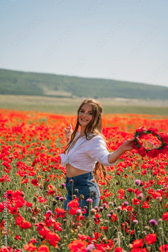 Happy woman in a poppy field in a white shirt and denim skirt with a wreath of poppies on her head posing and enjoying the poppy field. Happy woman in a poppy field in a white shirt and denim skirt with a wreath of poppies on her head posing and enjoying the poppy field.