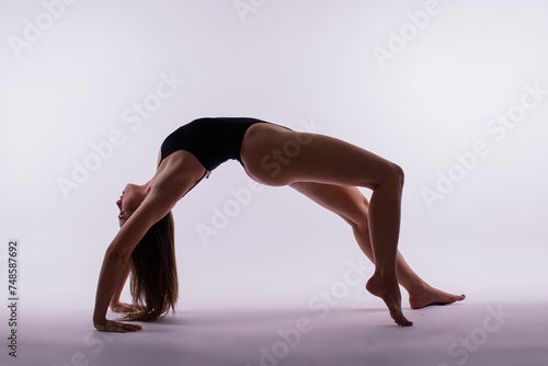 Young beautiful female yoga posing on a gray studio background
