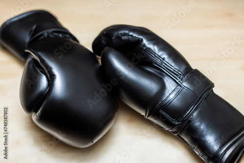 sport gloves. black fighting gloves lie on a light wooden table  close-up  sport concept