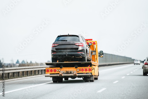 Emergency roadside assistance in action as a tow truck carries a broken down SUV on the highway.