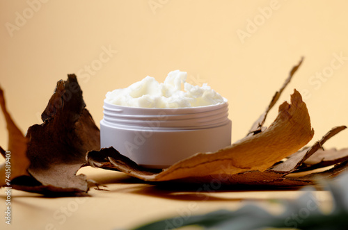 Shea butter in a white bowl on light beige background. Product moisturizer natural for beauty, cosmetics and spa.