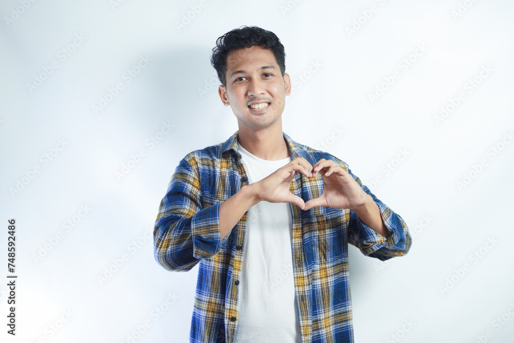 Adult Asian man smiling happy while making heart shape symbol with his hands Adult Asian man smiling happy while making heart shape symbol with his hands