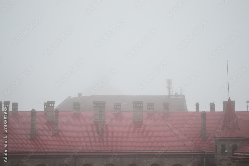 Old town in the fog. Roofs of houses on a foggy morning in Lviv. Old houses in the fog. Fire station with a red roof in the fog. Ukraine.