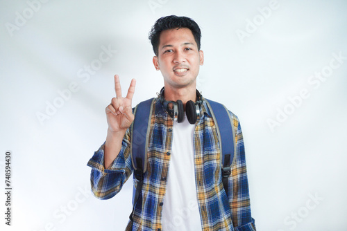 Asian man student smiling at the camera and doing two fingers sign photo