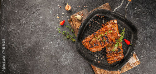 Grilled fresh lamb ribs with thyme, garlic and chili in pan. Long banner format. top view. copy space for text