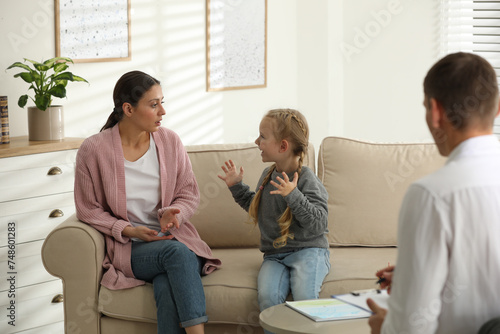 Child psychotherapist working with little girl and her mother in office photo