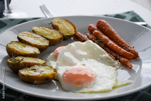 fried eggs with roasted potatoes and carrots on a white plate; homemade lunch