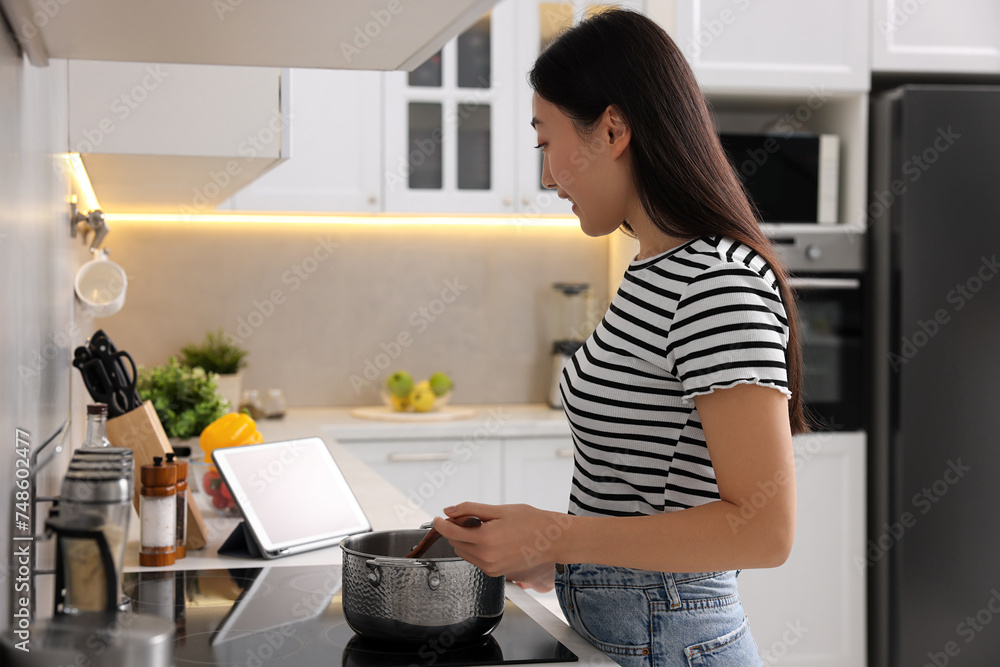 Woman looking at recipe on tablet while cooking in kitchen Woman looking at recipe on tablet while cooking in kitchen