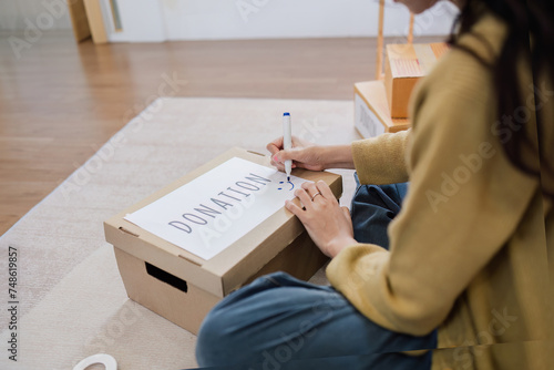 Asian woman sitting and writing on a box to prepare for donation. Help poor people
