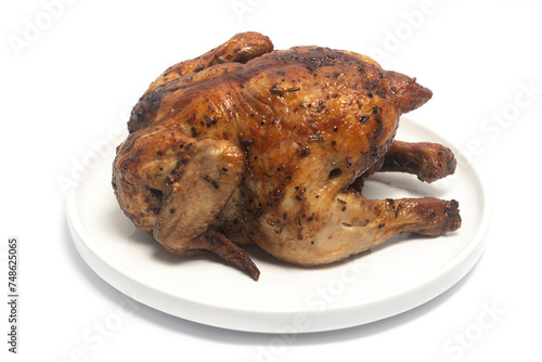 A whole delicious roasted chicken seasoned with herbs in a white plate isolated on white background clipping path
