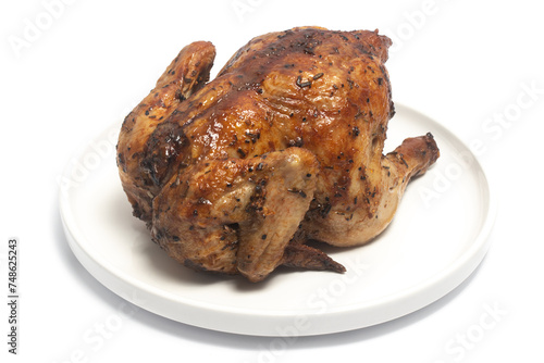 A whole delicious roasted chicken seasoned with herbs in a white plate isolated on white background clipping path