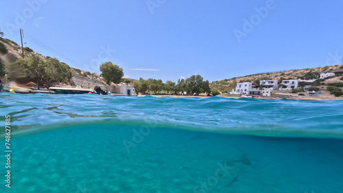 Underwater split photo of paradise crystal clear sea beach of Agios Georgios in main port of Irakleia island covered in Armirikia trees providing natural shade, small Cyclades, Greece photo