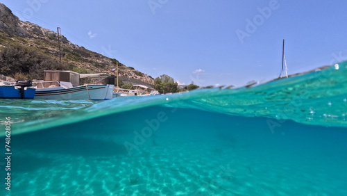 Fototapeta Naklejka Na Ścianę i Meble -  Underwater split photo of traditional fishing wooden boats in port of Iraklia island, small Cyclades, Greece