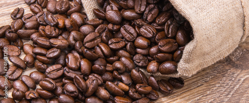 Heap of dark roasted coffee grains in jute bag