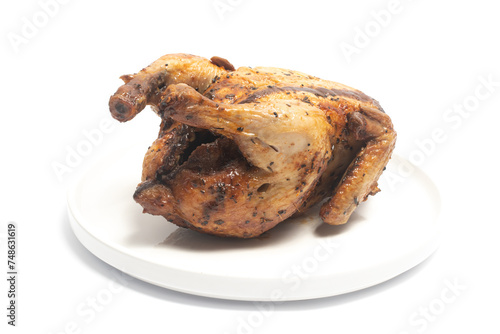 A whole delicious roasted chicken seasoned with herbs in a white plate isolated on white background clipping path