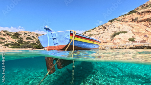 Underwater split photo of traditional wooden fishing boat anchored in turquoise sea of rocky bay in island of Crete, Greece