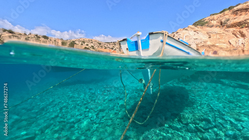 Underwater split photo of traditional fishing boat anchored in small secluded fjord and paradise beach of Tourkopigado  Iraklia island  Small Cyclades  Greece