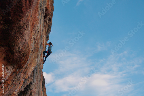 silhouette of a girl climber. rock climber girl climbs an overhanging rock.