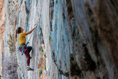 A woman climbs a rock, a strong girl trains strength and endurance, extreme sport, rock climbing..