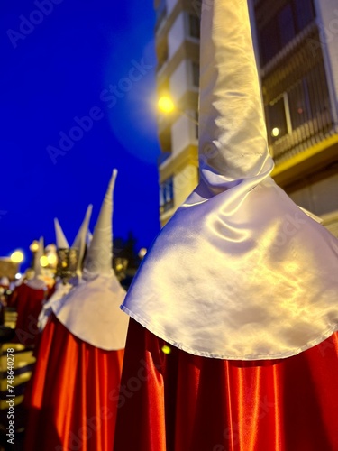 Penitents in Pointed Hoods Marching in Evening Street Procession