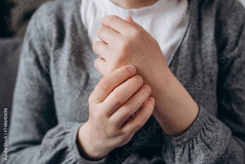 Close up of unhealthy young female massage hand with wrist pain, rheumatoid arthritis. Woman suffer from numbing pain in hand, numbness fingertip, arthritis inflammation, peripheral neuropathies photo