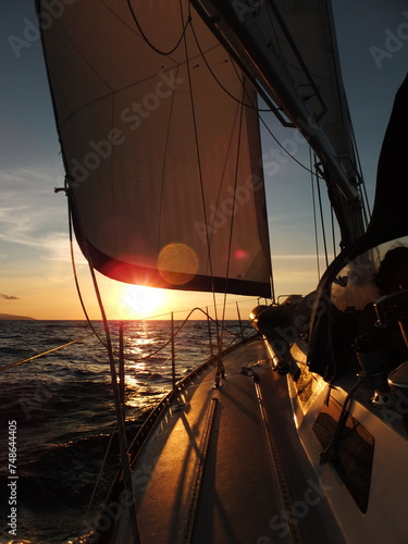 Sailboat sunset view verticall with sun behind the sail photo