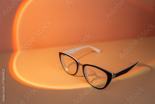 Vision glasses with black frames under orange light.
