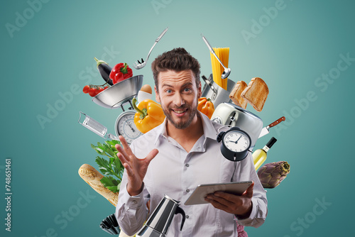 Happy man surrounded by kitchen utensils and connecting online