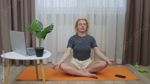 A nice young woman turning on relaxation music, meditating on an orange mat in a room and then interrupted by a call. photo