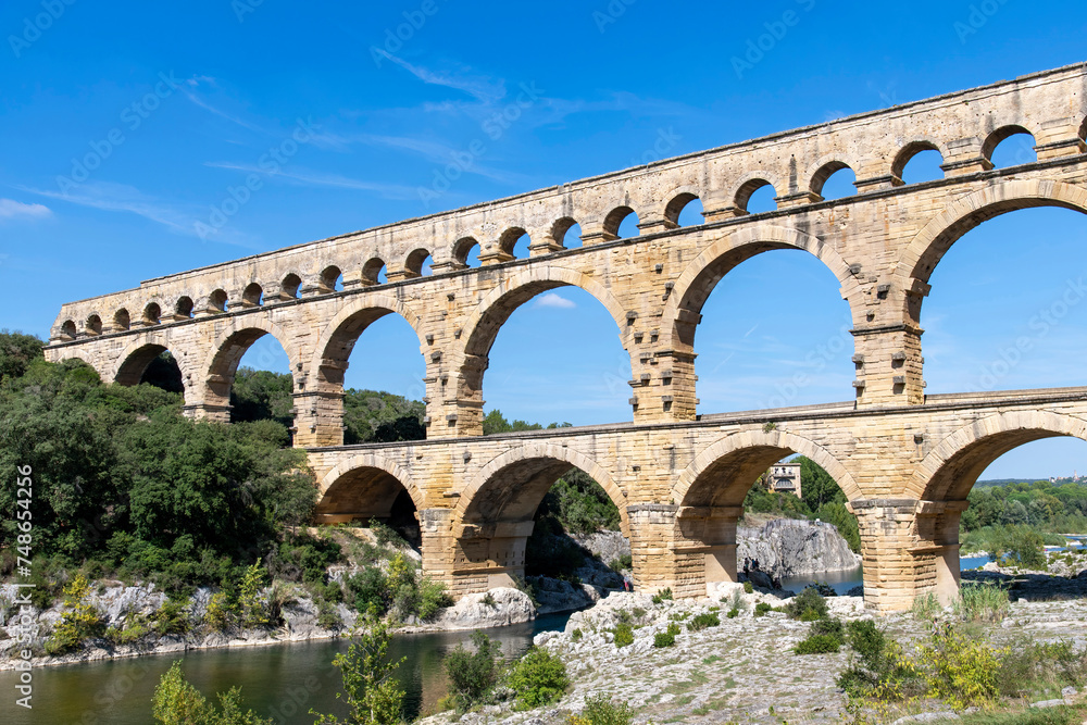 Low angle view of the aqueduct bridge Pont du Gard over the Gardon river near Vers-Pont-du-Gard, France with well-preserved arched tiers, built by 1st-century Romans
