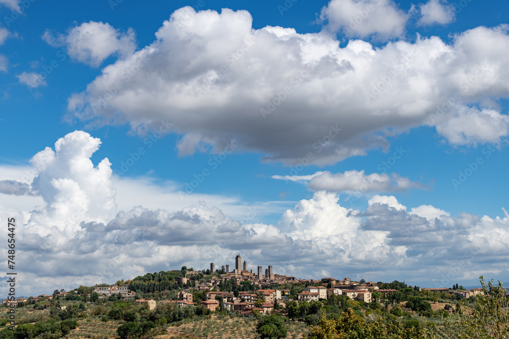 Panoramic view of skyline of walled medieval hill town San Gimignano in Tuscany, Italy known as the Town of Fine Towers famous for its medieval architecture of tower houses with dramatic clouded sky