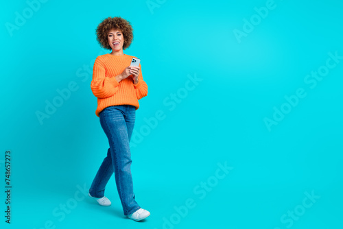Photo of cheerful adorable latin girl wear trendy orange clothes walk store mall center empty space isolated on blue color background