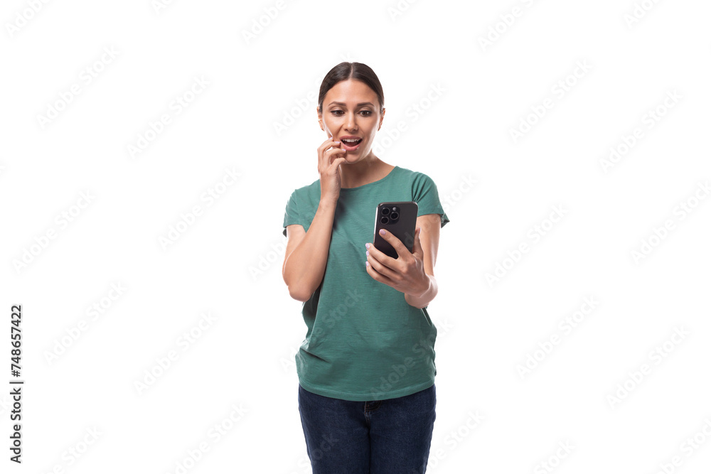 30 year old brunette woman with ponytail dressed in a green basic T-shirt reads messages on the phone with surprise 30 year old brunette woman with ponytail dressed in a green basic T-shirt reads messages on the phone with surprise