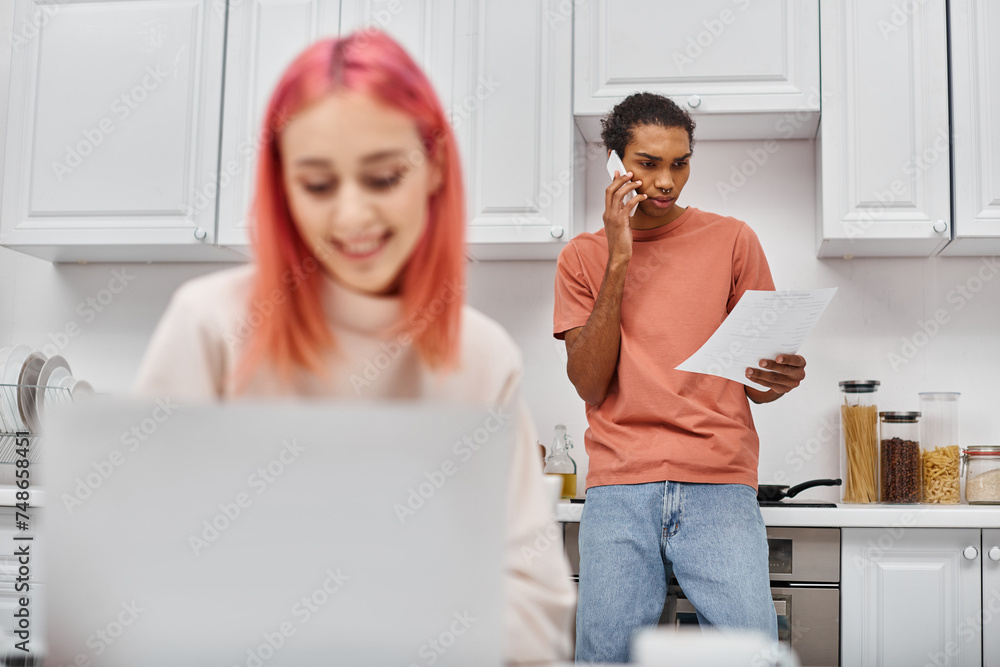 focus on concentrated african american man talking by phone near his jolly blurred girlfriend focus on concentrated african american man talking by phone near his jolly blurred girlfriend