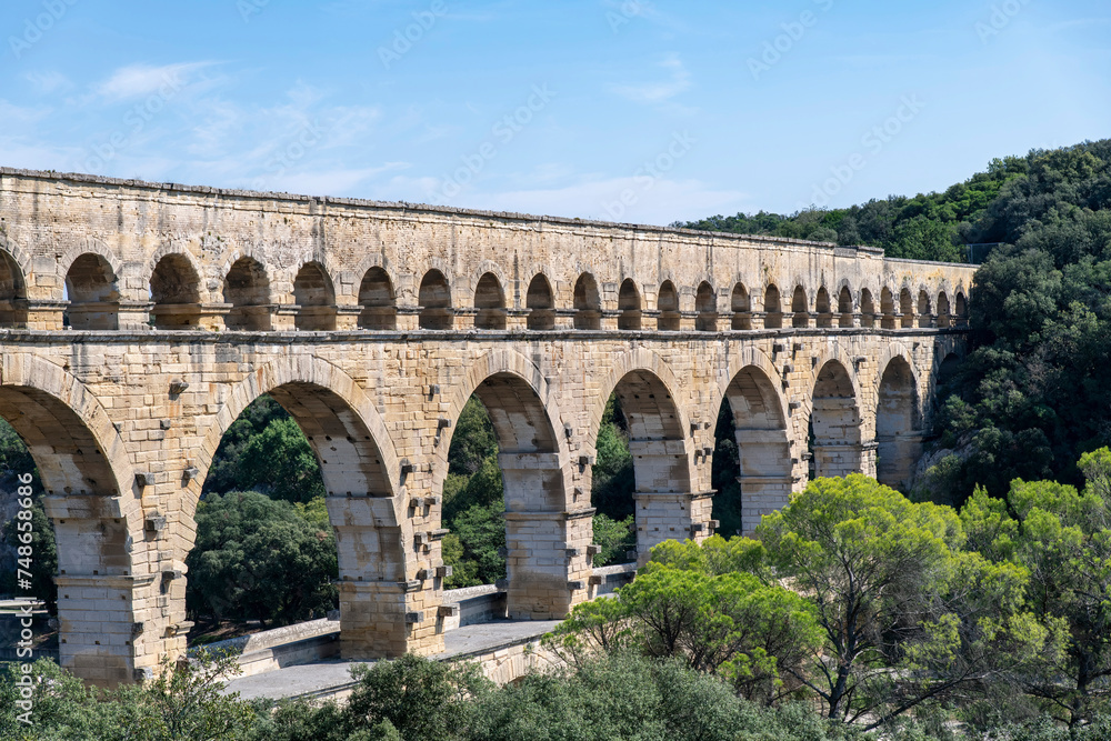 High angle partial view of the aqueduct bridge Pont du Gard over the Gardon river near Vers-Pont-du-Gard, France with well-preserved arched tiers, built by 1st-century Romans