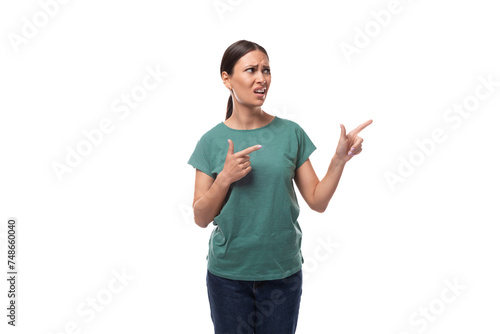 active smiling young caucasian brunette woman in a green t-shirt points with her hand at the space for advertising