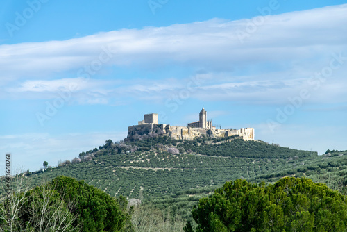 Panoramic view over agricultural landscape with olive orchards and medieval fortress Fortaleza de la Mota on top of hill in city of Alcalá la Real, Spain