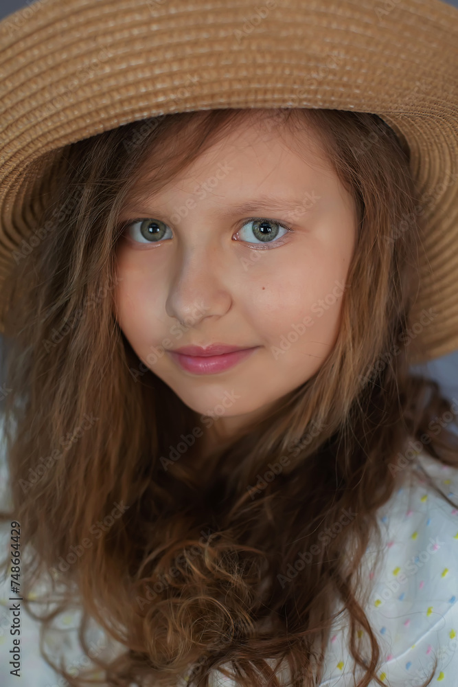 a brown-haired girl with curly hair in a white dress and a straw hat on a gray background a brown-haired girl with curly hair in a white dress and a straw hat on a gray background