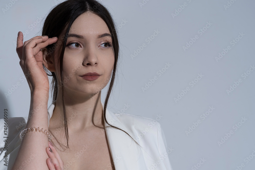 Portrait of attractive Caucasian young brunette woman in casual clothes, white jacket in studio. Style, fashion, elegance. Portrait of attractive Caucasian young brunette woman in casual clothes, white jacket in studio. Style, fashion, elegance.