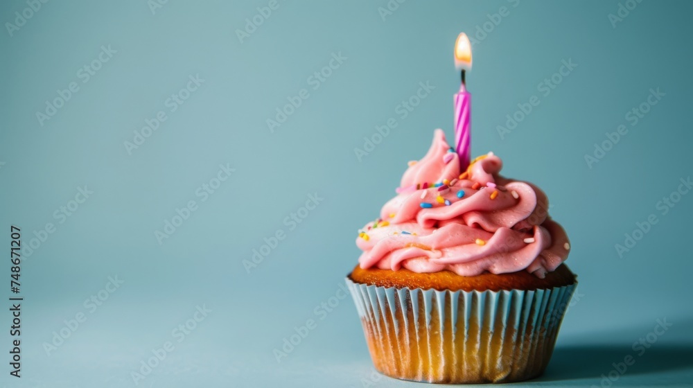 Pink frosted birthday cupcake with candle. Tasty, happy, delicious and sweet. Isolated on blue background. Copy space. Pink frosted birthday cupcake with candle. Tasty, happy, delicious and sweet. Isolated on blue background. Copy space.
