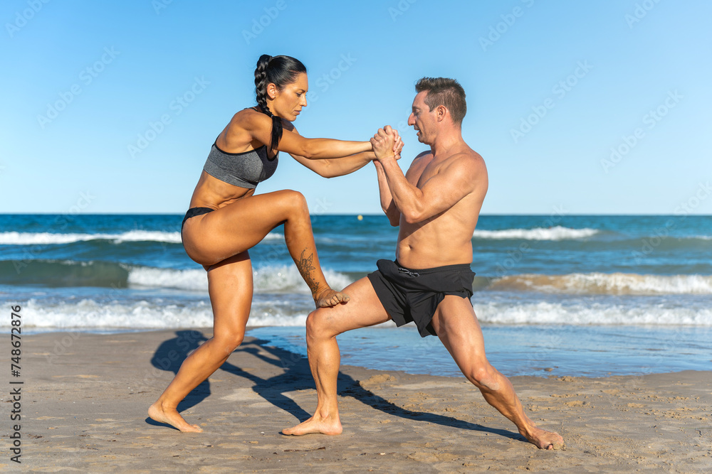Middle aged couple exercising together on the beach this summer Middle aged couple exercising together on the beach this summer