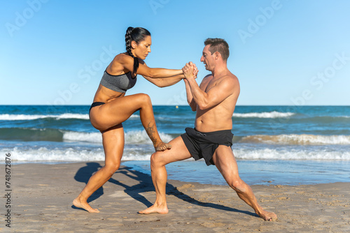 Middle aged couple exercising together on the beach this summer