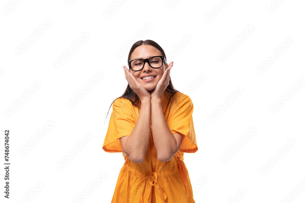 young positive smiling black-haired woman with glasses dressed in an orange summer dress getting ready to go on vacation