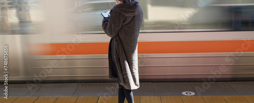 冬の駅で電車待ちの若い女性と通過中の電車の様子 photo