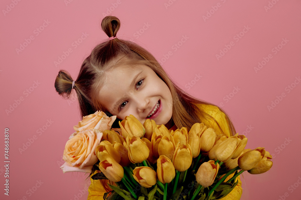 Little smiling girl holding flowers on pink background. International women's day. Little smiling girl holding flowers on pink background. International women's day.