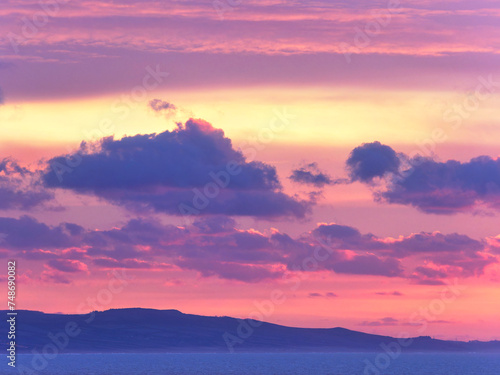 Fototapeta Naklejka Na Ścianę i Meble -  A stormy winter sunrise over the jurassic coastline with fiery pink and gold tinged clouds