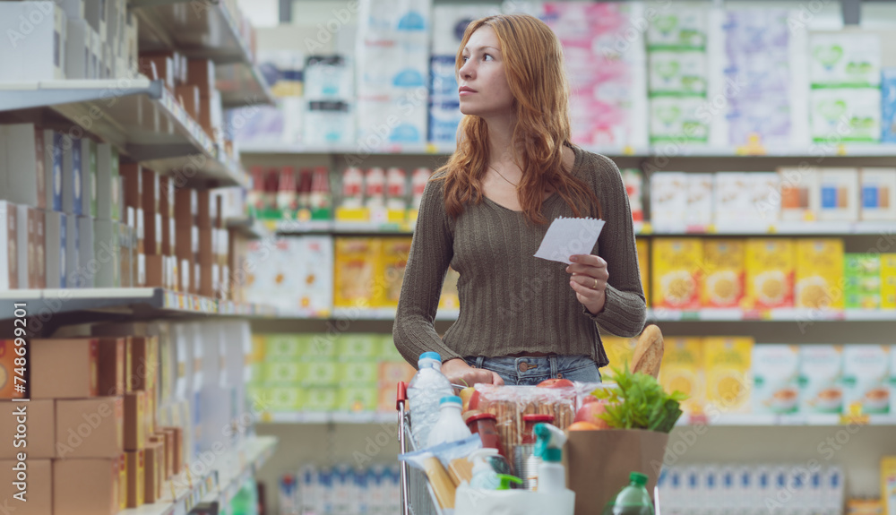 Woman doing grocery shopping and holding a shopping list