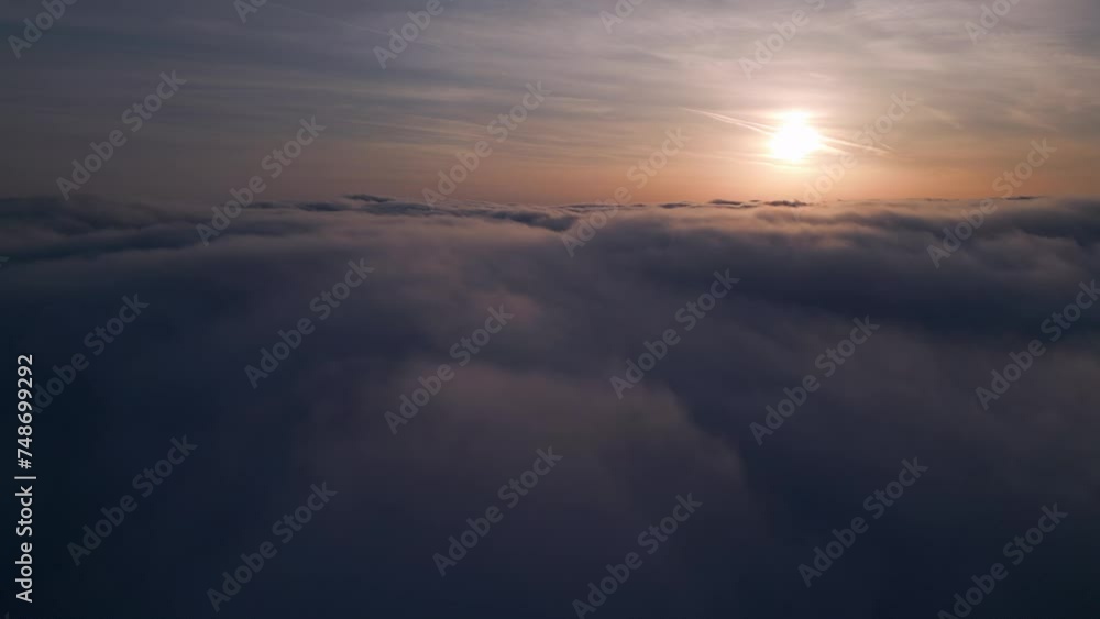 A serene drone view of the sun rising above a vast expanse of fluffy clouds. A serene drone view of the sun rising above a vast expanse of fluffy clouds.