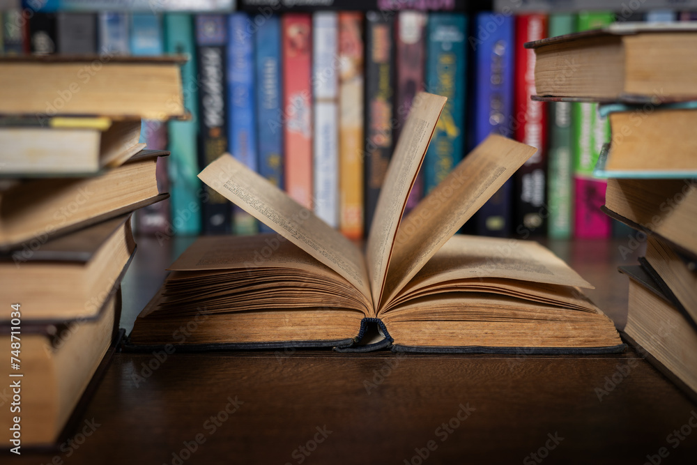 Fototapeta premium opened book, lying on the bookshelf in library